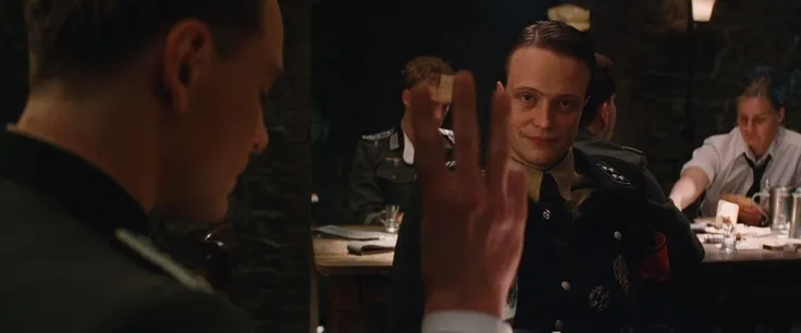 Scene from Inglorious Basterds: Brad Pitt's Allied spy has just been detected by August Diehl's Nazi general by way of a culturally atypical gesture, and the latter looks on knowingly